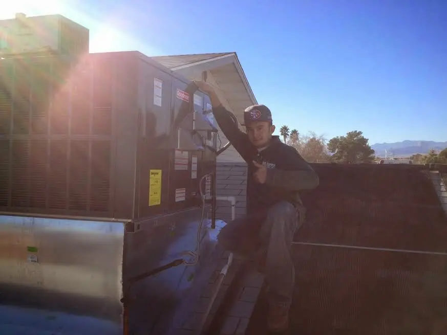 HVAC technician performing Air Duct Cleaning on a rooftop unit in Smithtown